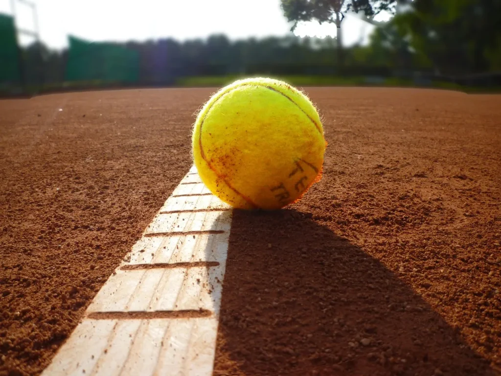 Tennis ball about to cross the out line.